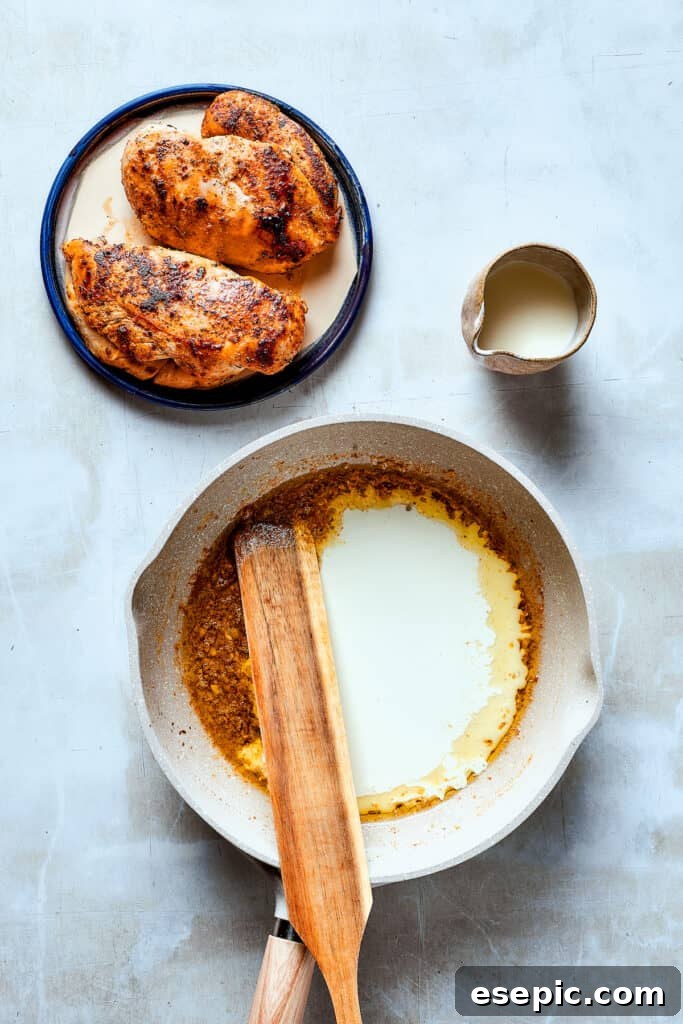 A wooden spoon gently stirring a creamy white sauce in a skillet, ensuring a smooth consistency.