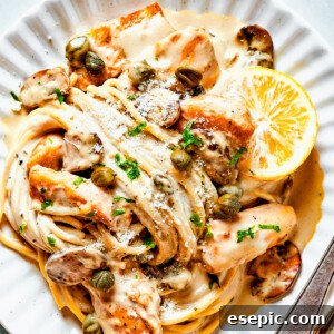 Chicken in caper-lemon sauce with pasta on a pale dinner plate.