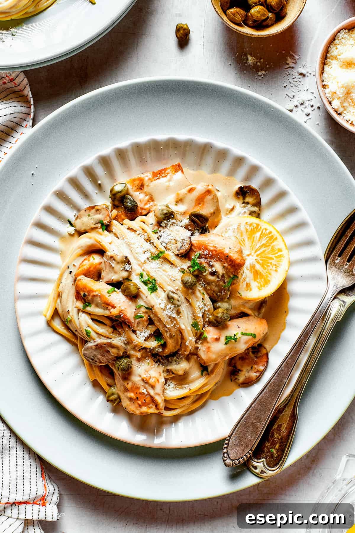 Close-up shot of tender pasta spirals coated in creamy piccata sauce, intertwined with pieces of chicken and mushrooms.