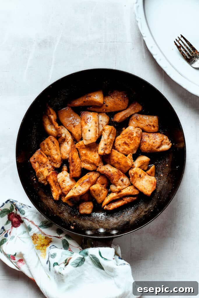 Chicken strips browning in a hot skillet, creating flavorful fond at the bottom of the pan.