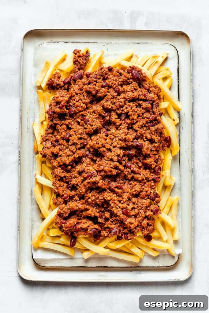 You’ll crave the hot, cheesy goodness of homemade Chili Cheese Fries! This is a fun party appetizer that can double as a family-style meal. A baking sheet with french fries covered in chili.