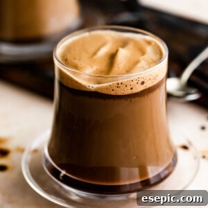 A glass mug with Caffe Macchiato and another mug set right behind it.