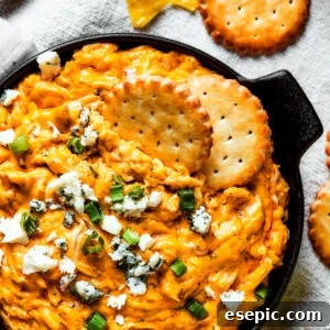 Overhead shot of a serving of buffalo dip with crackers, blue cheese, and green onions.