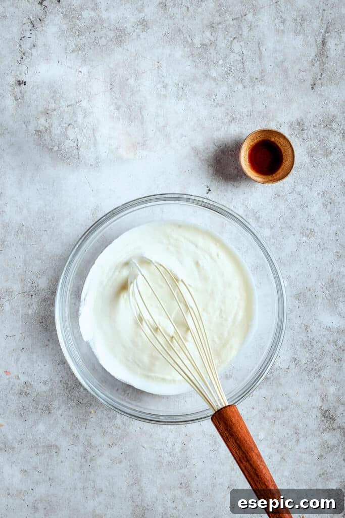 Decadent Banana Pudding Cupcakes 13 The process of whipping heavy cream with vanilla extract in a mixer, forming soft peaks for the delicate cupcake topping.