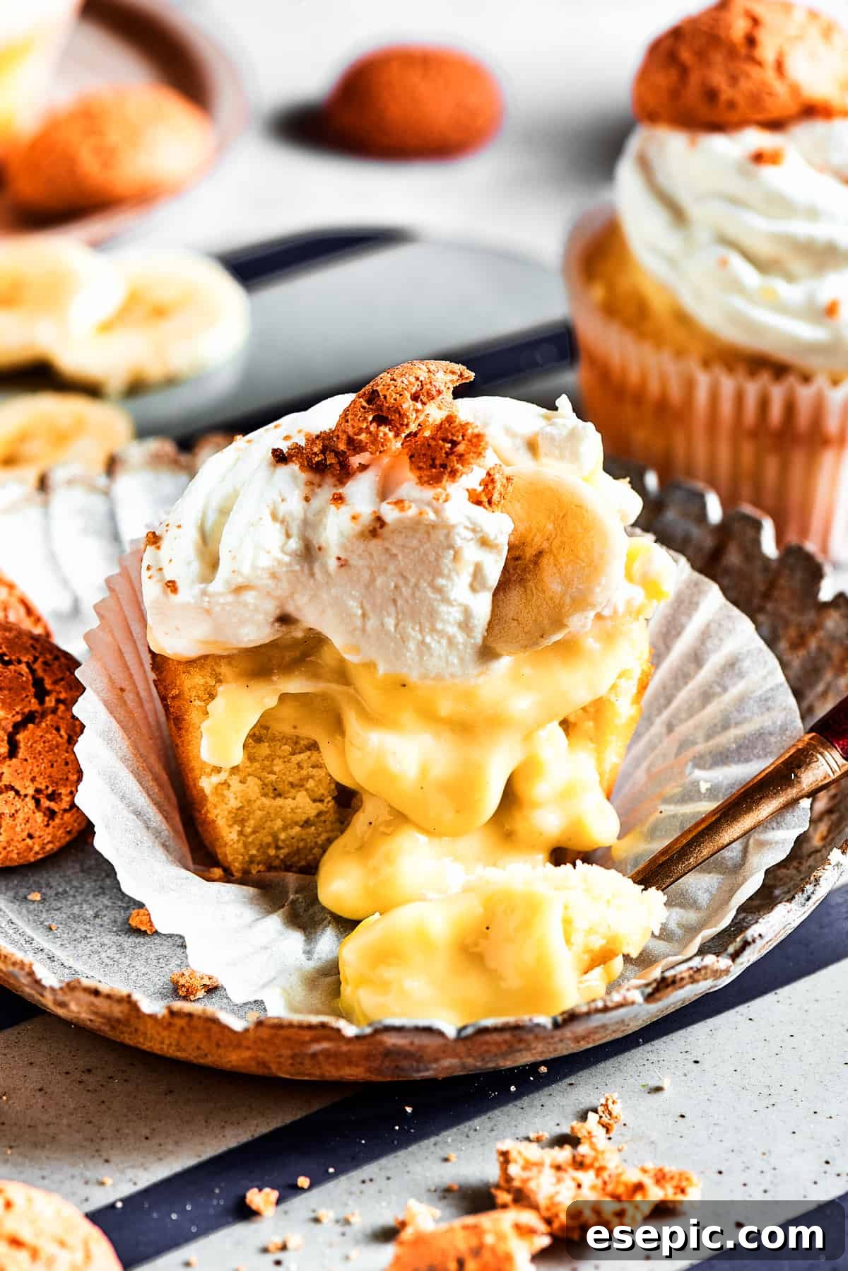 Decadent Banana Pudding Cupcakes 4 A perfectly halved banana pudding cupcake, with its paper wrapper peeled back, revealing the luscious, creamy banana pudding filling gently oozing from its core.