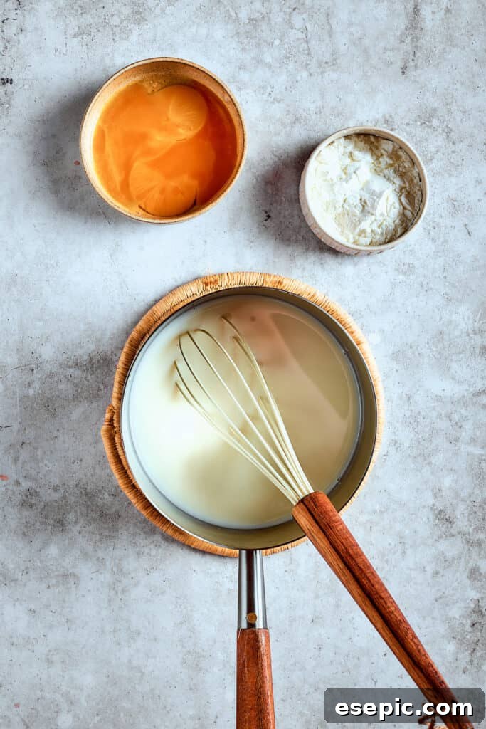 Decadent Banana Pudding Cupcakes 9 A whisk stirring milk and sugar in a saucepan over medium heat, ensuring even dissolution and preventing scorching.
