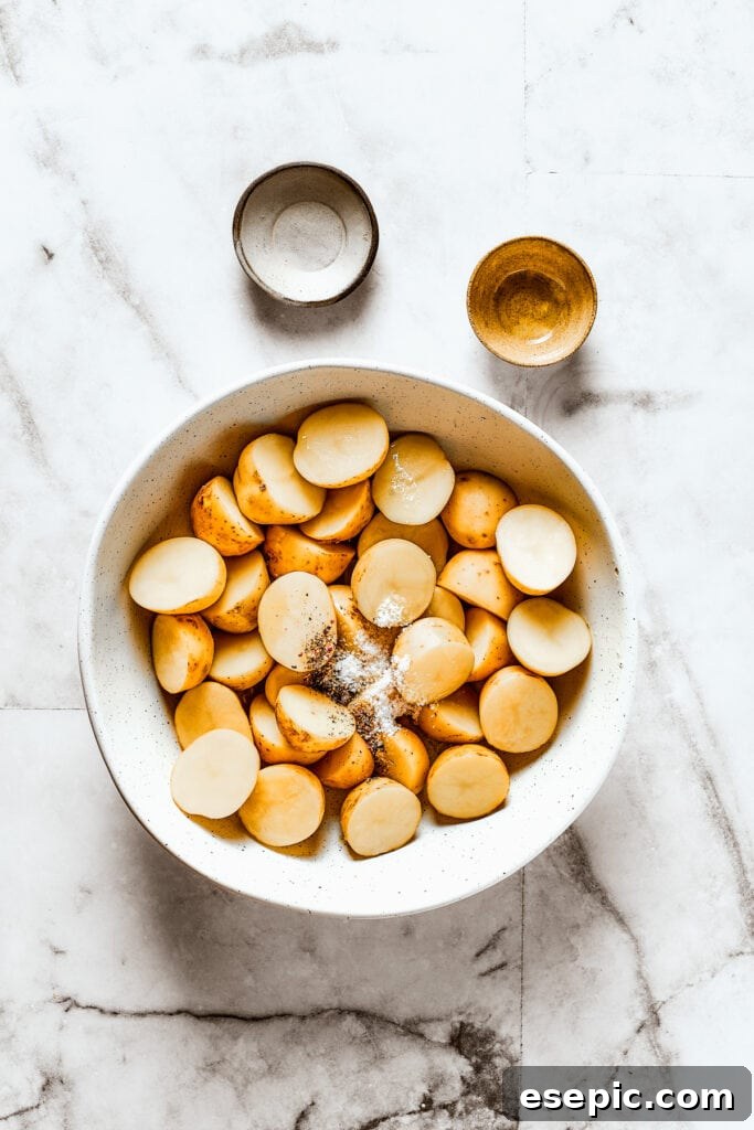 Cut potatoes in a bowl with salt, pepper, and oil, ready for seasoning.