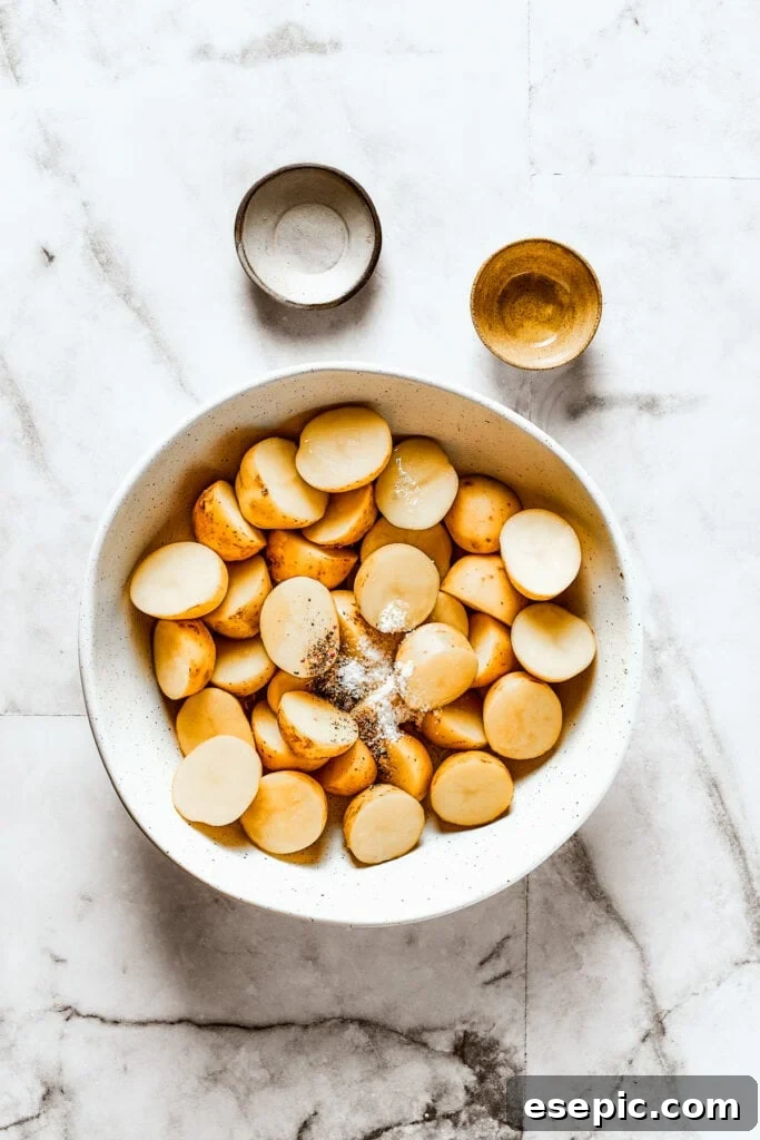 Cut potatoes in a bowl with salt, pepper, and oil, ready for seasoning.