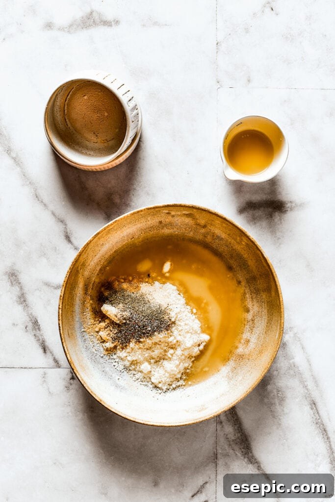 Seasonings, parmesan, and melted butter in a shallow dish, forming the flavorful crust mixture.