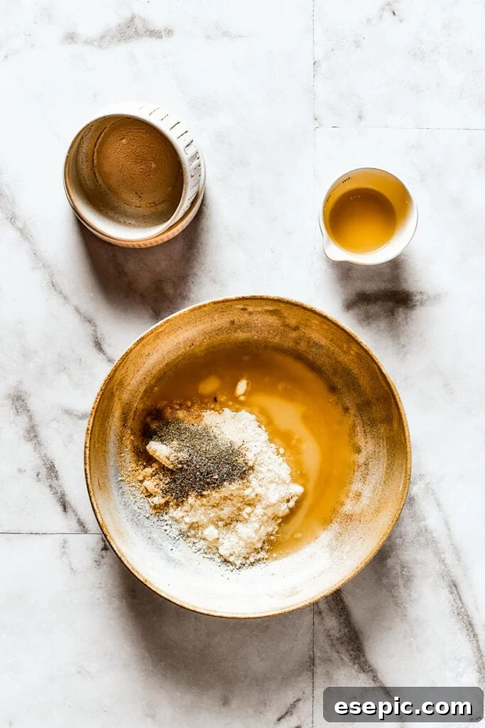 Seasonings, parmesan cheese, and melted butter in a shallow dish, forming a mixture.