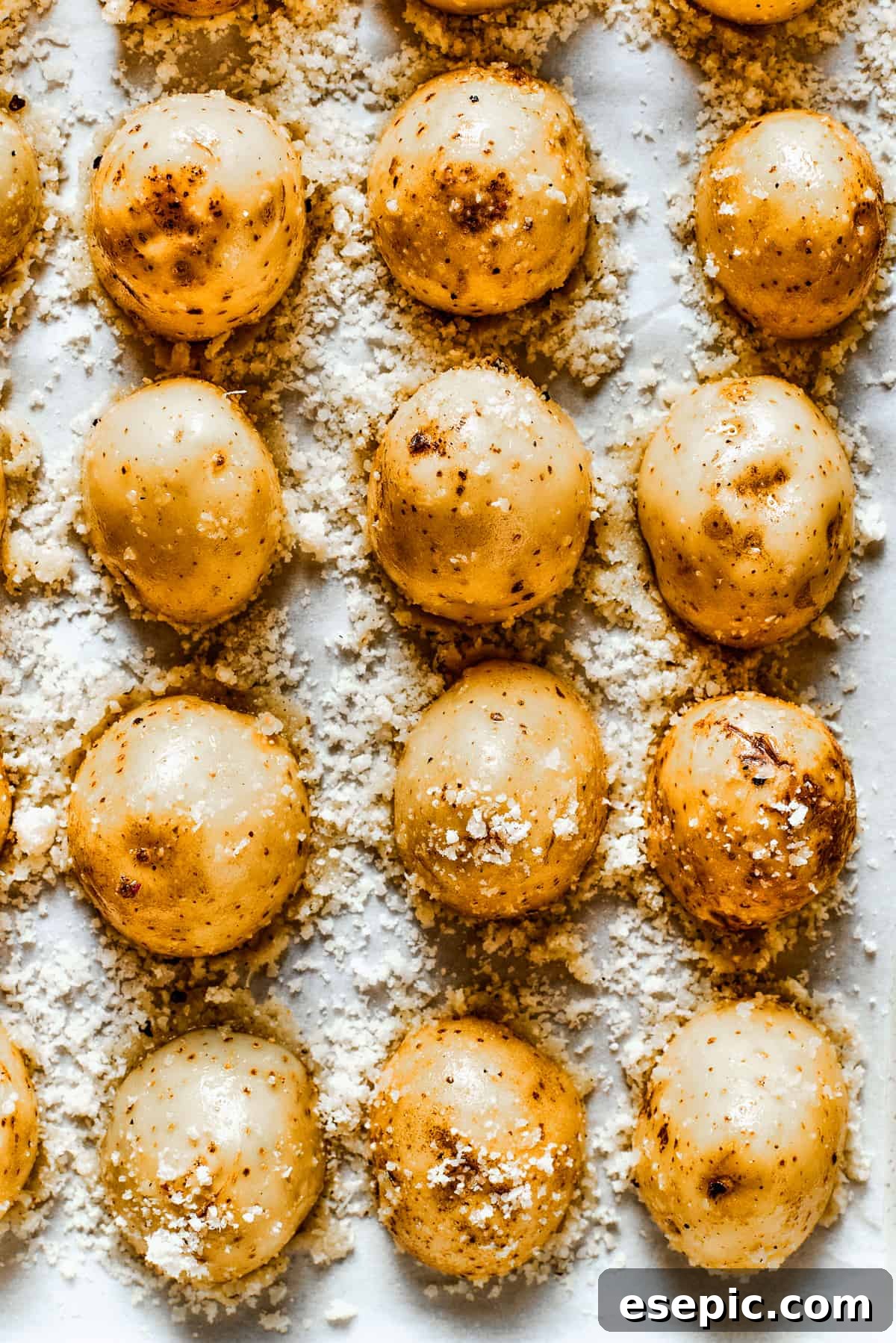 Close-up of baked parmesan-crusted potatoes in a baking dish, showcasing their golden, crispy crust.