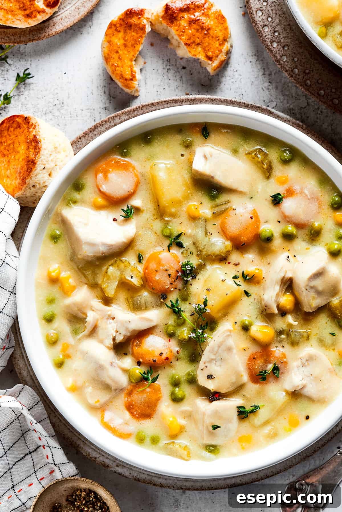 Creamy and hearty chicken pot pie soup with tender chicken and vegetables, garnished with fresh thyme and served alongside warm biscuits. Hearty Chicken Pot Pie Soup in a bowl with fresh thyme garnish, accompanied by warm, flaky biscuits, perfect for a comforting meal.