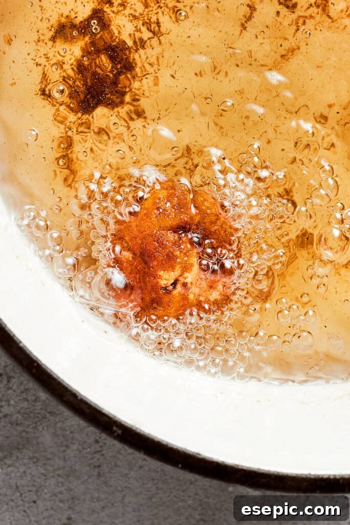Close up view of a mac and cheese bite frying in oil.