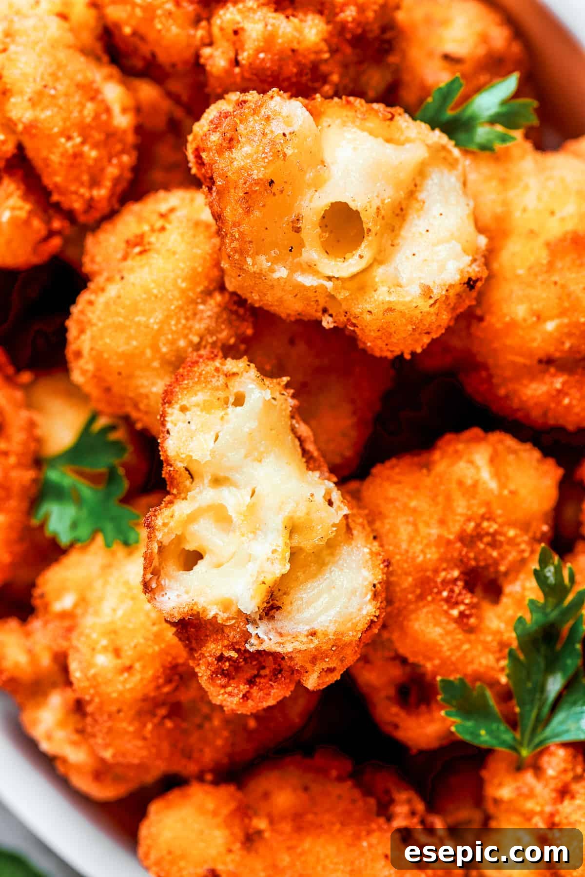 Close-up image of fried mac and cheese bites cut in half to showcase its texture inside.