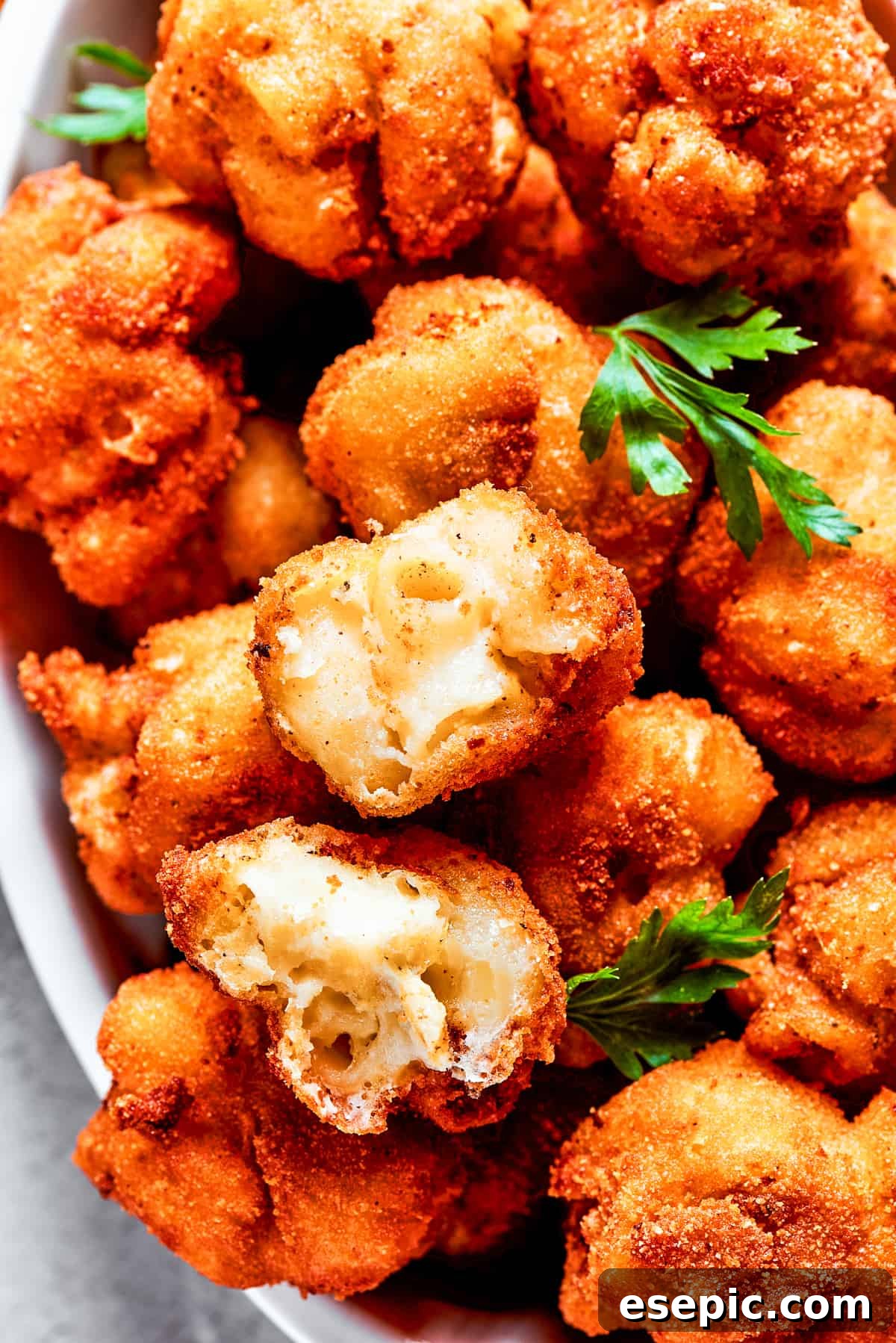 Overhead view of a serving bowl full of mac and cheese bites garnished with fresh herbs.