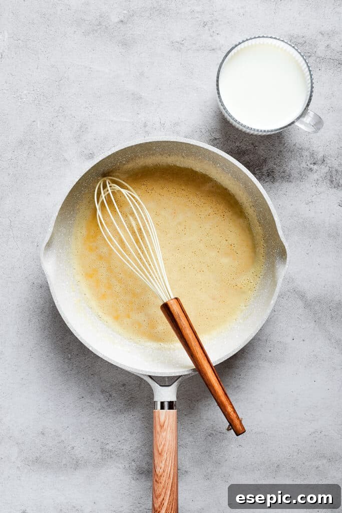 A saucepan filled with a roux and a whisk.