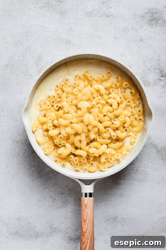 A sauce pan with macaroni sitting on top of a cheese sauce.
