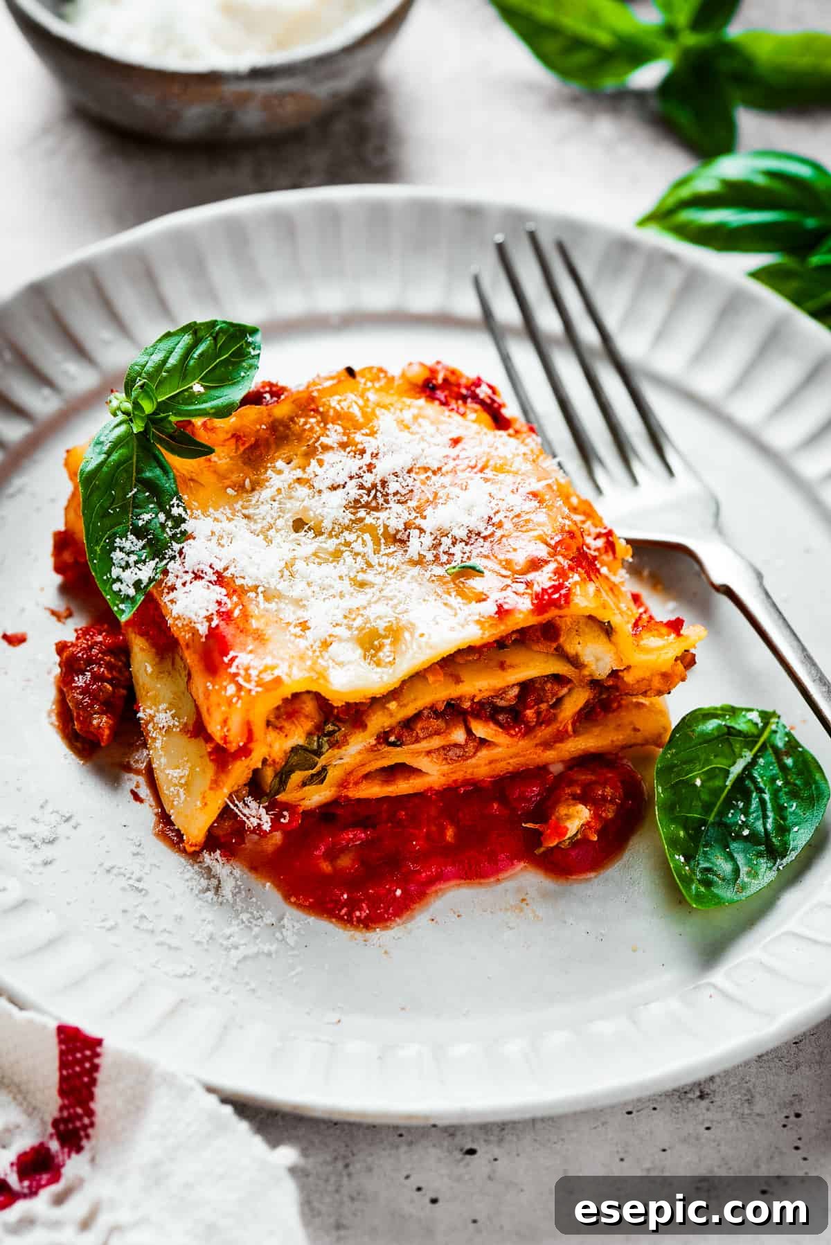 A lasagna roll on a plate with basil leaves and a fork.