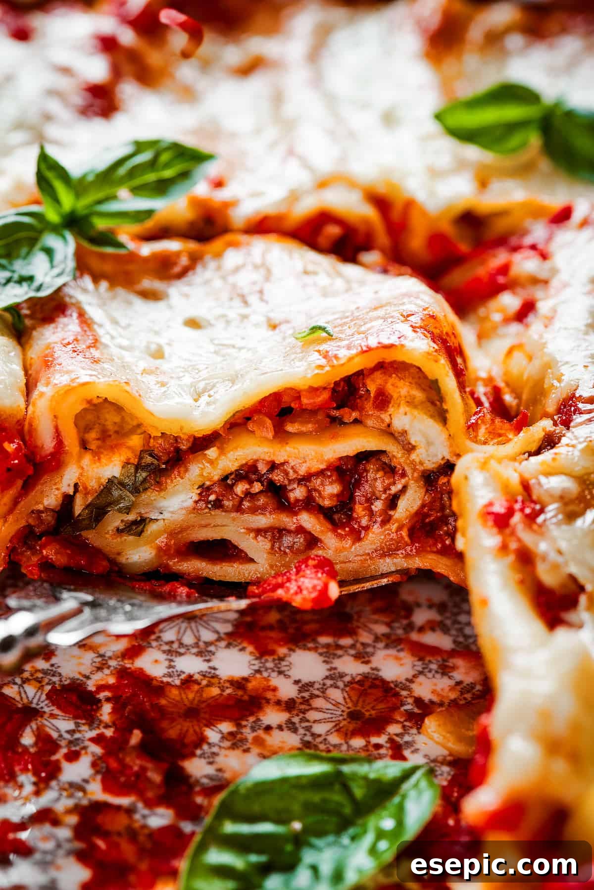 Close up of a lasagna roll up on a plate topped with basil.
