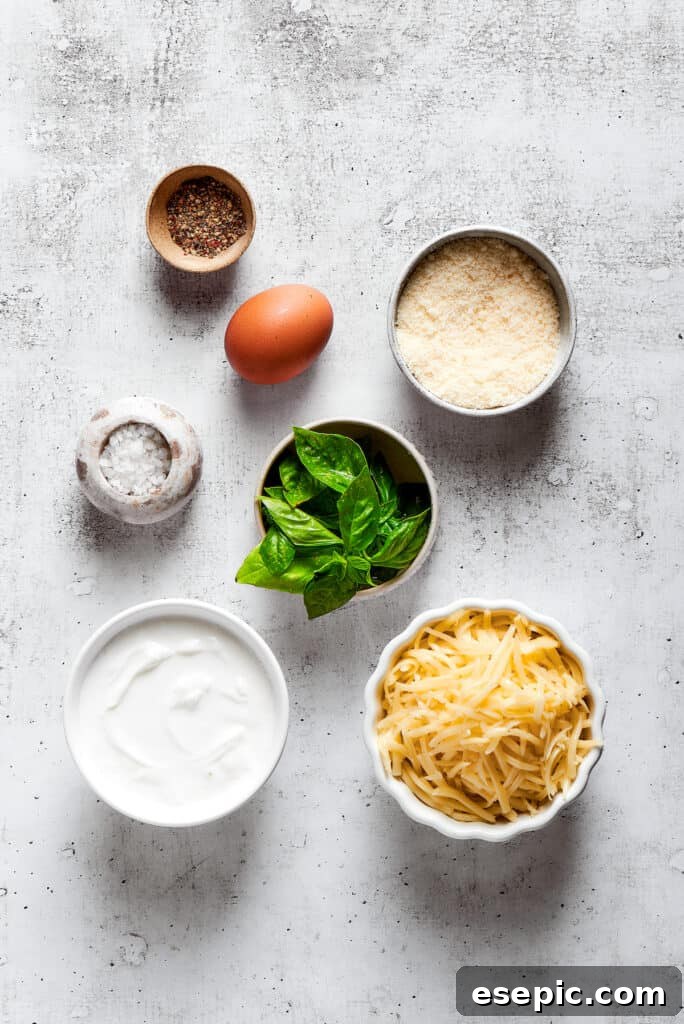 Overhead view of the ingredients needed for cheese filling: a bowl of parmesan, a bowl of mozzarella, a container of ricotta, a bowl of basil, an egg, a bowl of salt, and a bowl of pepper.