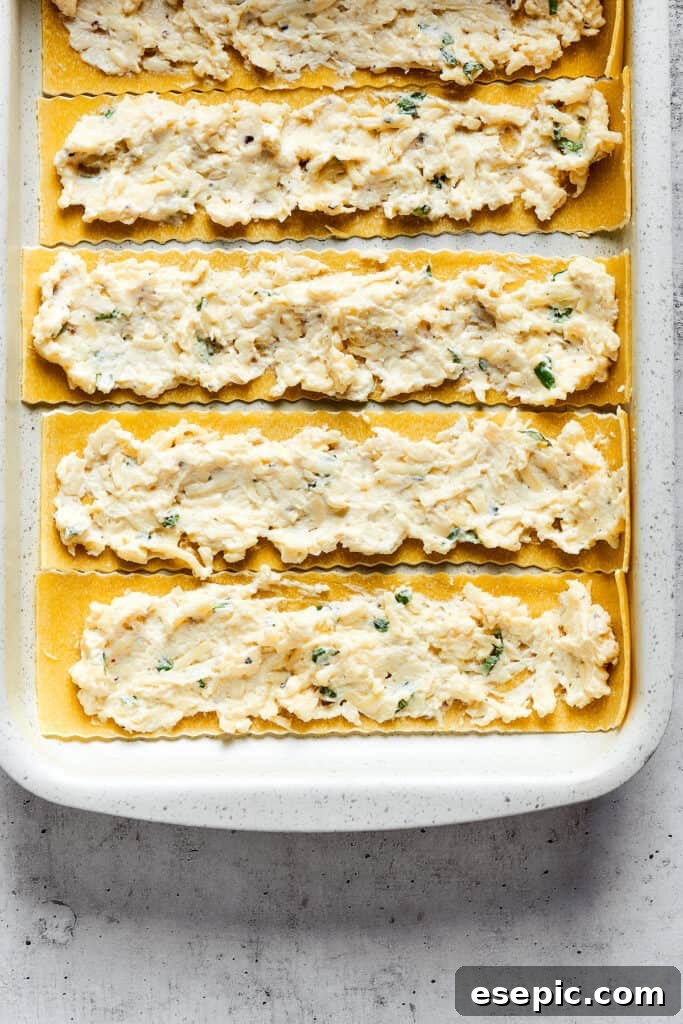 Overhead view of lasagna noodles with a cheese mixture spread over them.