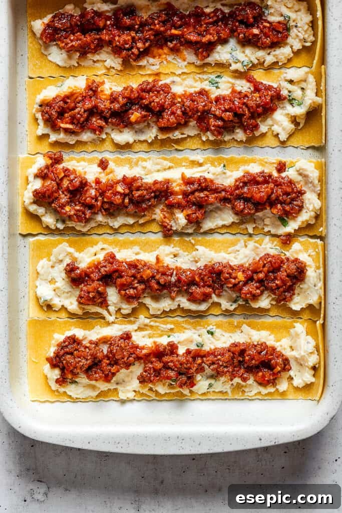 Overhead view of lasagna noodles covered with a cheese mixture and a ragu.