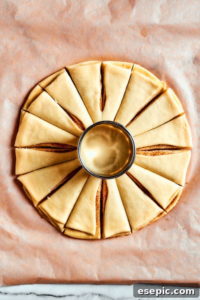 Overhead view of a star bread dough cut into 16 segments, with a glass in the middle.