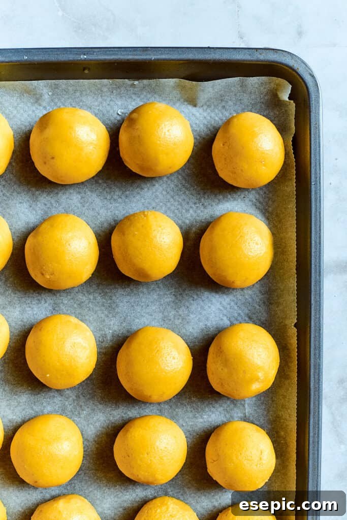 Overhead view of lemon cookie dough balls on a baking sheet.