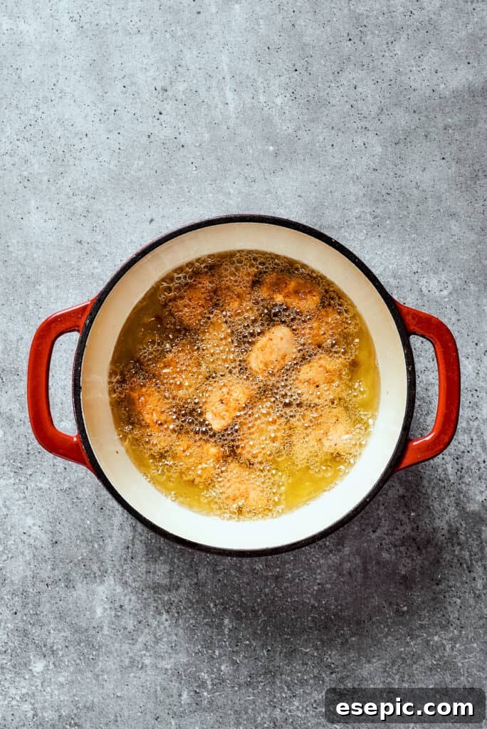Overhead view of chicken frying in a dutch oven.