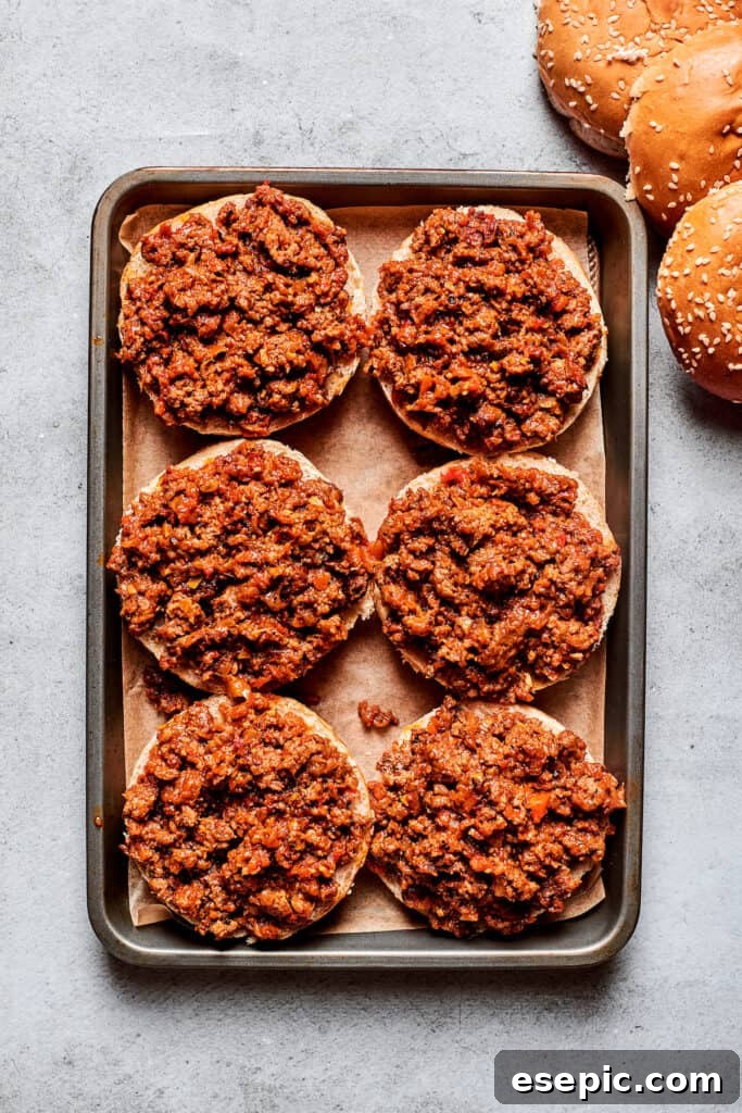 Six perfectly prepared pizza burgers, each with a hearty meat base, are neatly arranged on a baking sheet, ready for the next delicious layer.