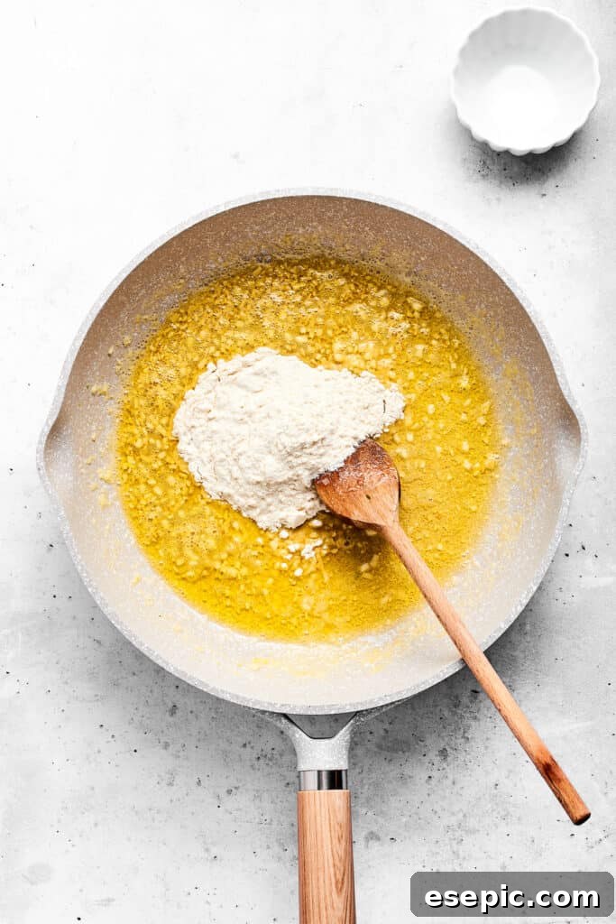 Adding flour to hot garlic butter in a saute pan.