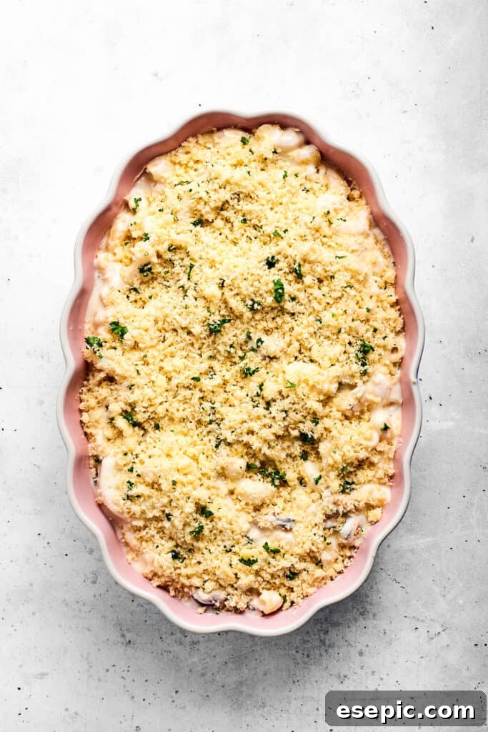 Seafood mac and cheese topped with parmesan breadcrumbs ready to go in the oven.