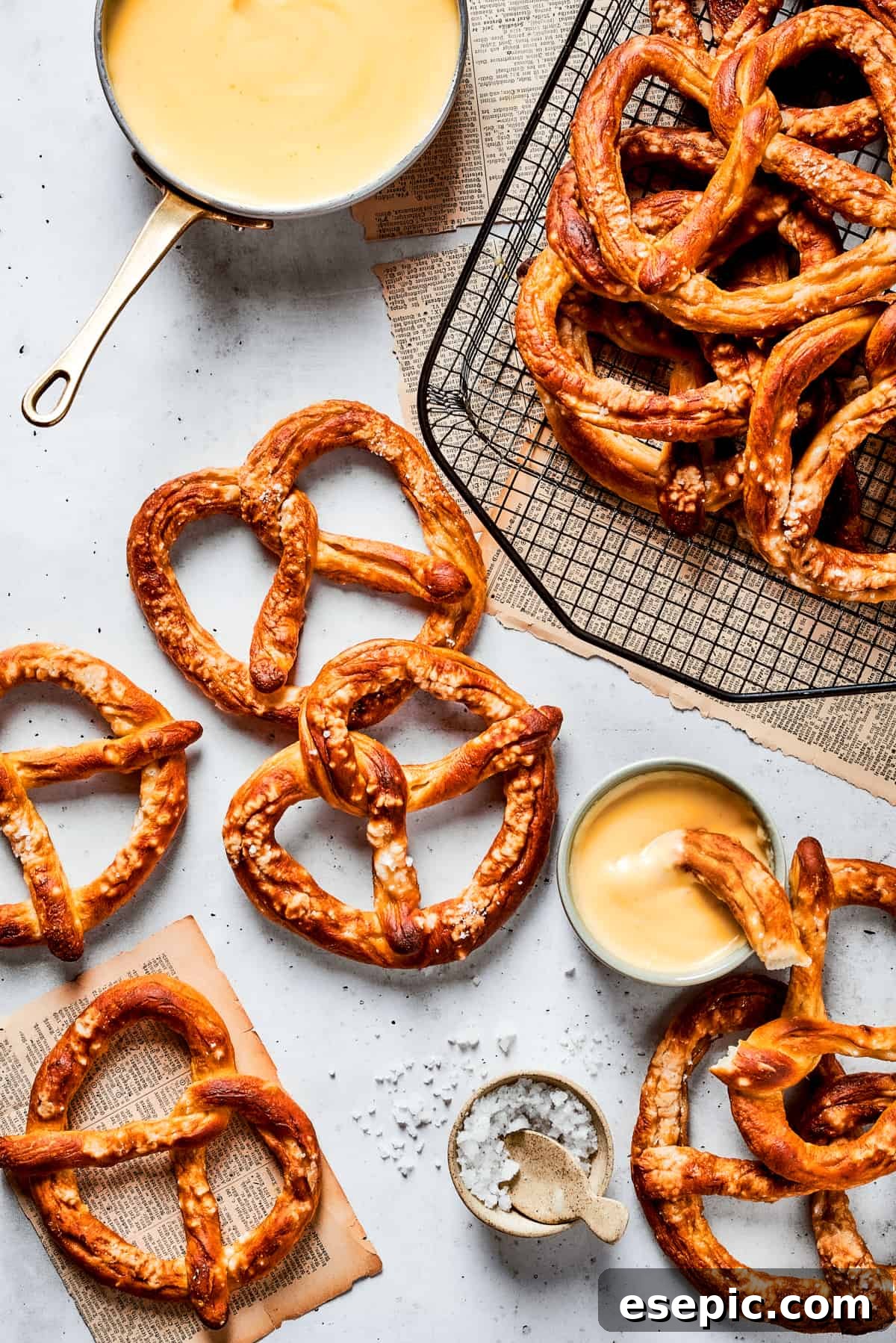 Master the art of homemade soft pretzels and pair them with our decadent, mustard-infused cheese dip. A serving of freshly baked soft pretzels arranged beautifully on a cooling rack, with a bowl of creamy, golden cheese sauce alongside, ready for dipping.