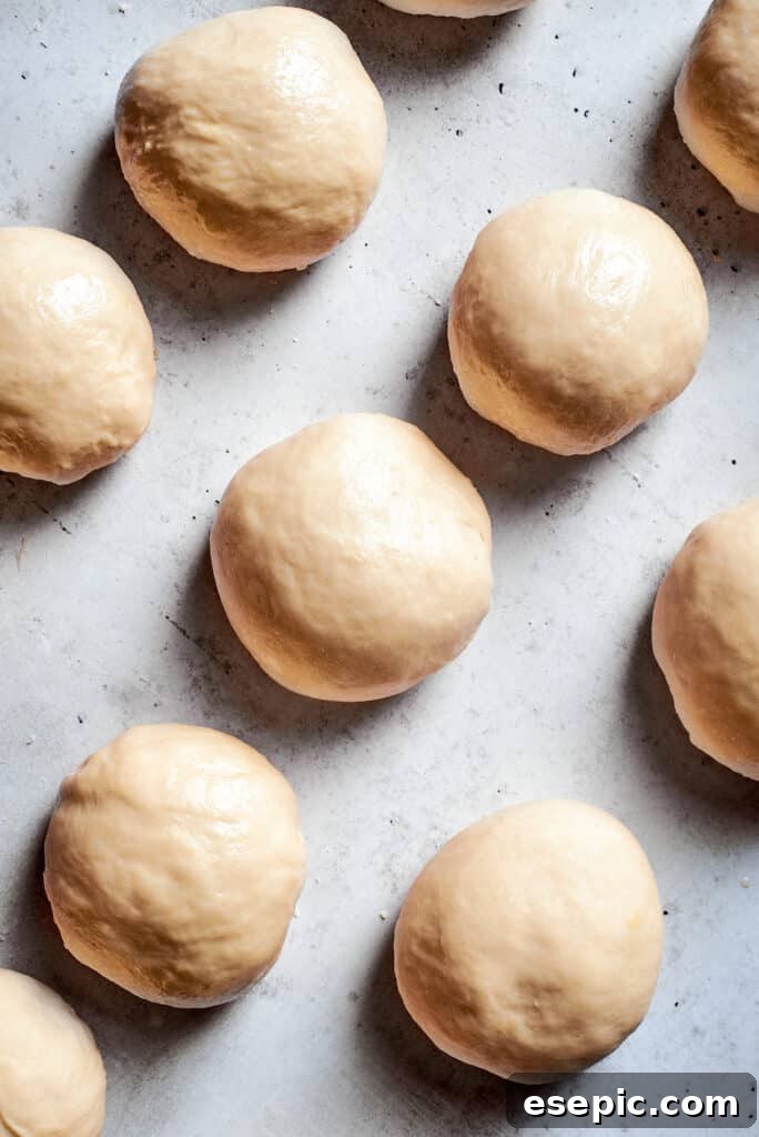 Master the art of homemade soft pretzels and pair them with our decadent, mustard-infused cheese dip. Twelve evenly portioned balls of soft pretzel dough rest on a clean white surface, awaiting their transformation into classic pretzel shapes.