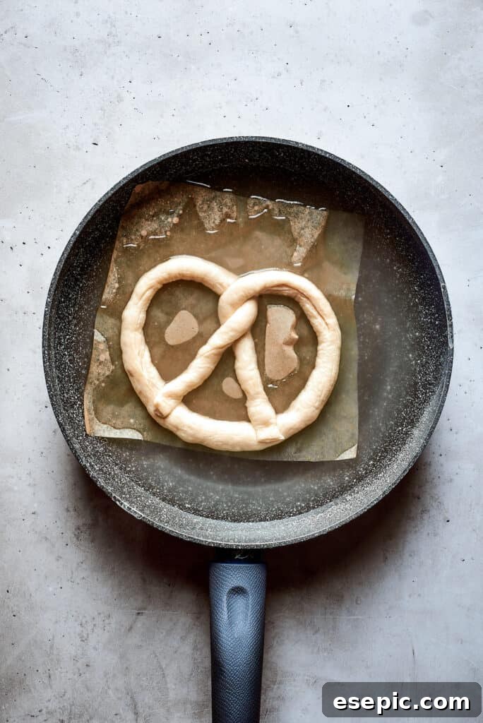 Perfectly Soft Homemade Pretzels 3 A top-down view of a single soft pretzel gracefully submerged in a large pot of boiling water, midway through its crucial baking soda bath.