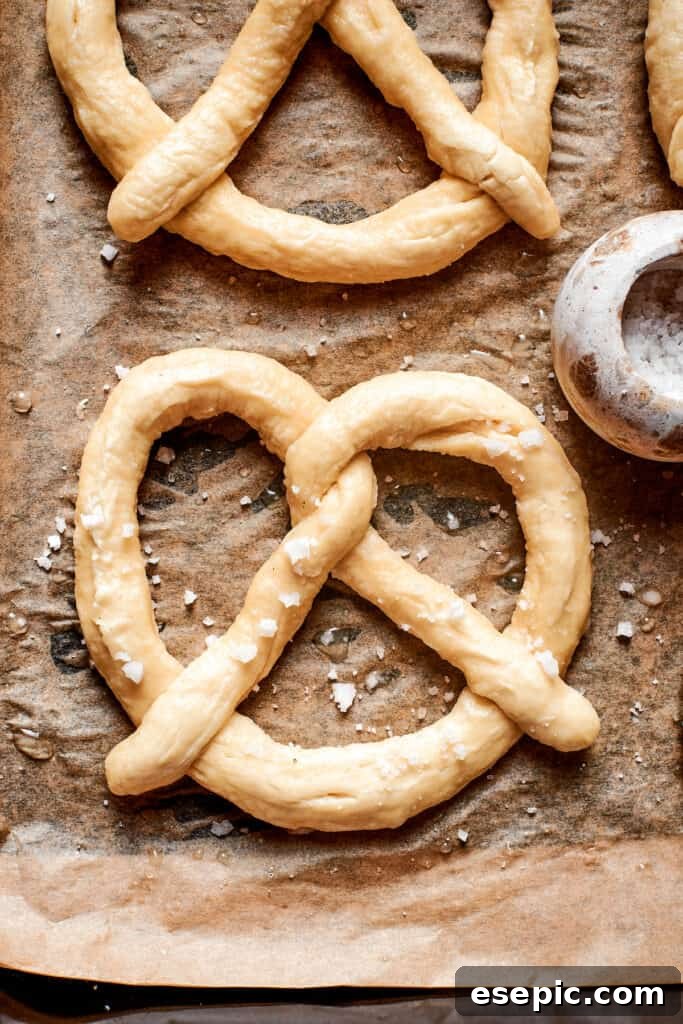 Perfectly Soft Homemade Pretzels 4 A baking sheet laden with several unbaked soft pretzels, freshly shaped and ready for their journey into the oven to achieve a perfect golden crust.