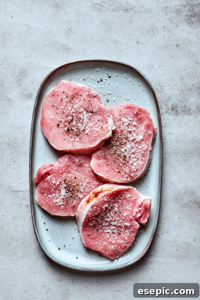 These Honey Garlic Pork Chops are the perfect blend of sweet-salty with a punch of extra flavor from minced garlic. Ready in 20 minutes! Pork chops seasoned with salt and pepper on a white tray.