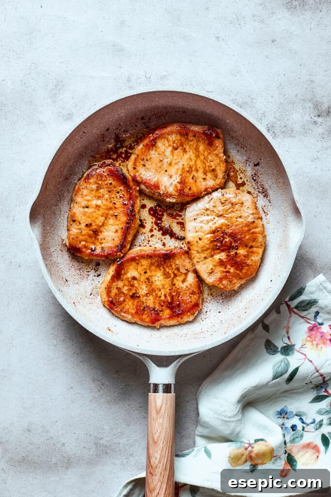 These Honey Garlic Pork Chops are the perfect blend of sweet-salty with a punch of extra flavor from minced garlic. Ready in 20 minutes! Pork chops sear in a white skillet.