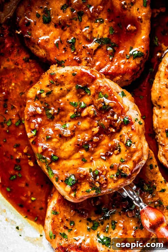 These Honey Garlic Pork Chops are the perfect blend of sweet-salty with a punch of extra flavor from minced garlic. Ready in 20 minutes! Close-up image of a spoon holding up a pork chop.