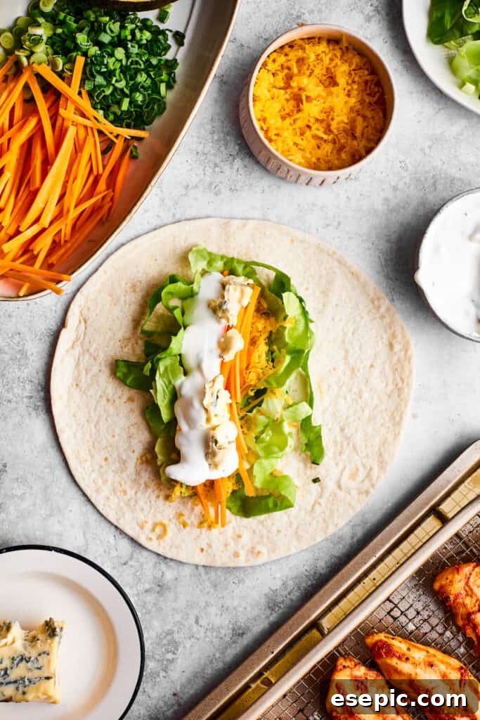 Ranch dressing being drizzled generously over a tortilla base with fresh vegetables, preparing for the Buffalo Chicken Wrap filling.