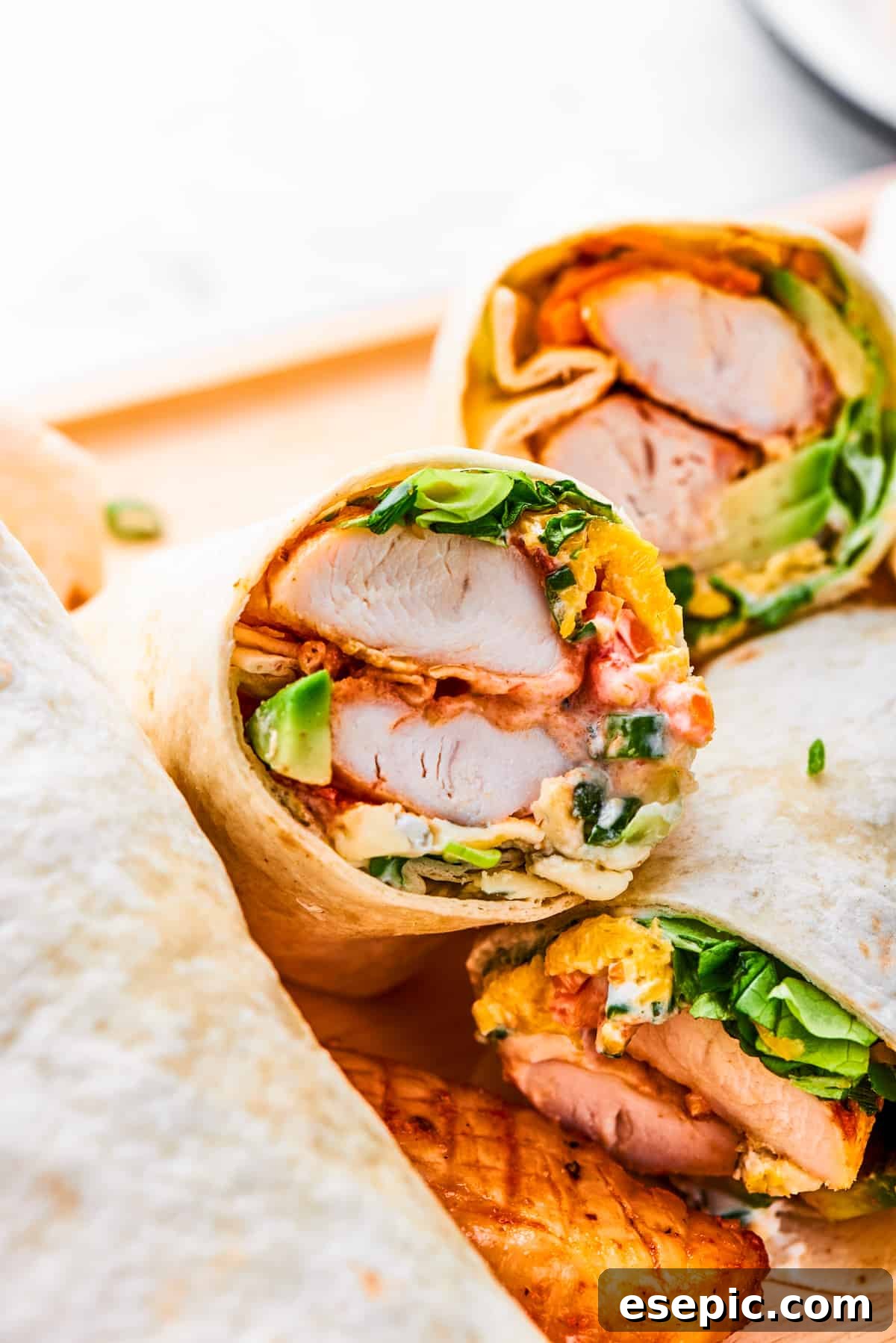 A perfectly halved Buffalo Chicken Wrap showcasing the rich layers of spicy chicken, creamy dressing, and fresh vegetables inside a warm tortilla.