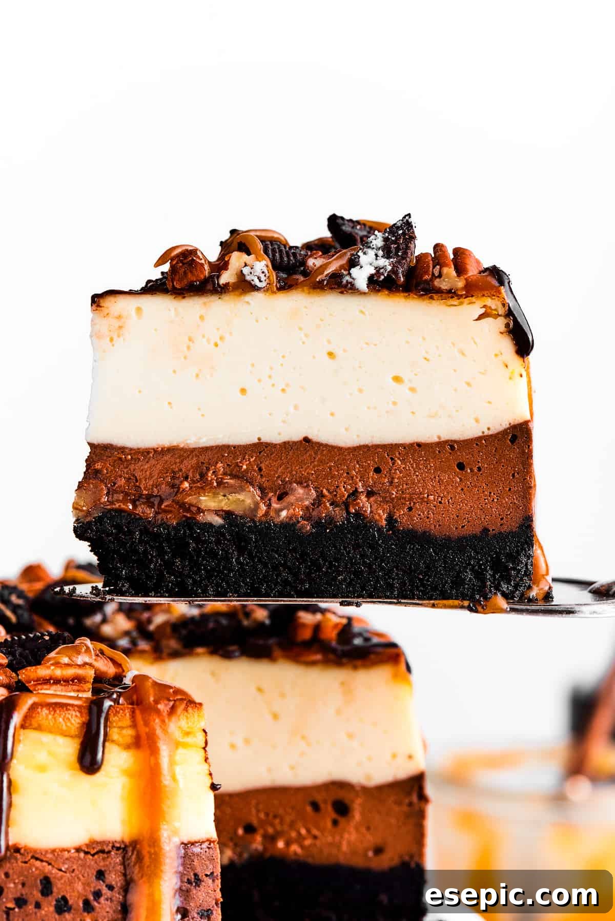 A cake server holding up a slice of turtle cheesecake.
