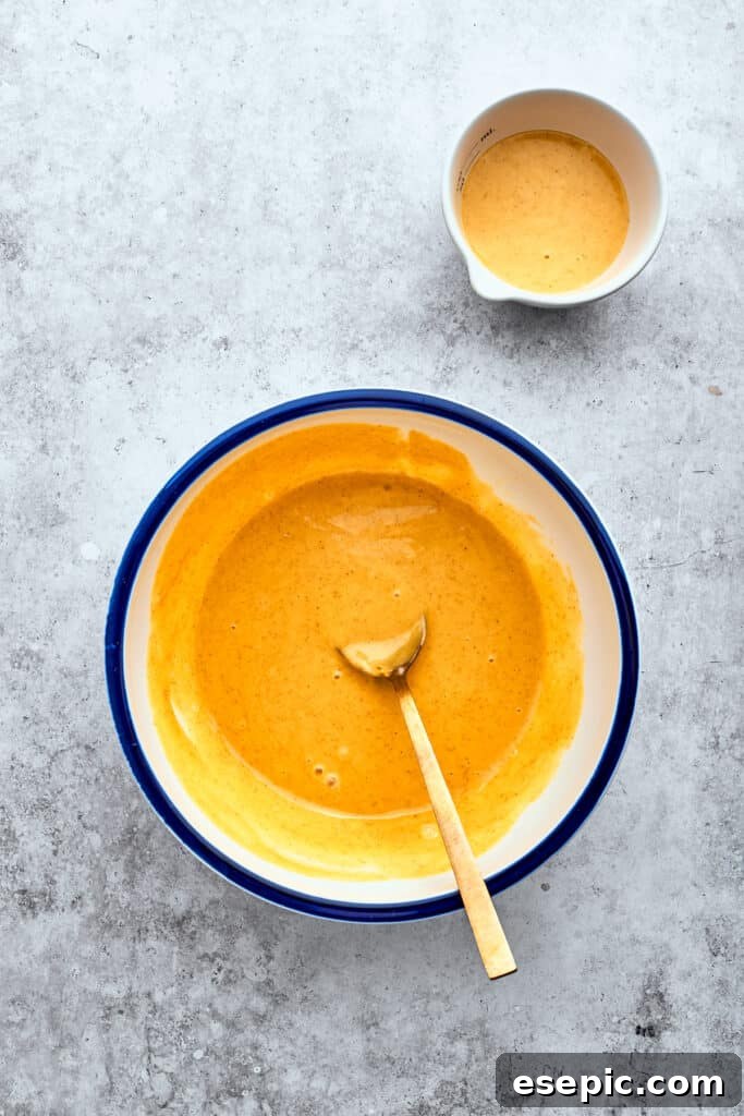 A wooden spoon combines a bright honey mustard marinade in a bowl.