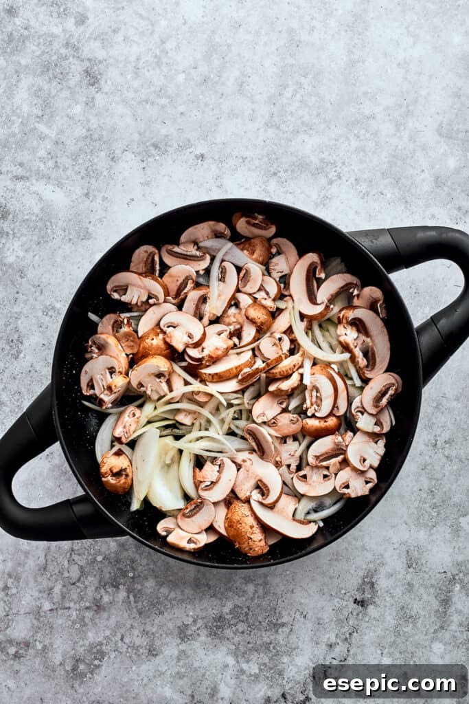 Garlic, onion, and sliced mushrooms are added to a cast iron pot.