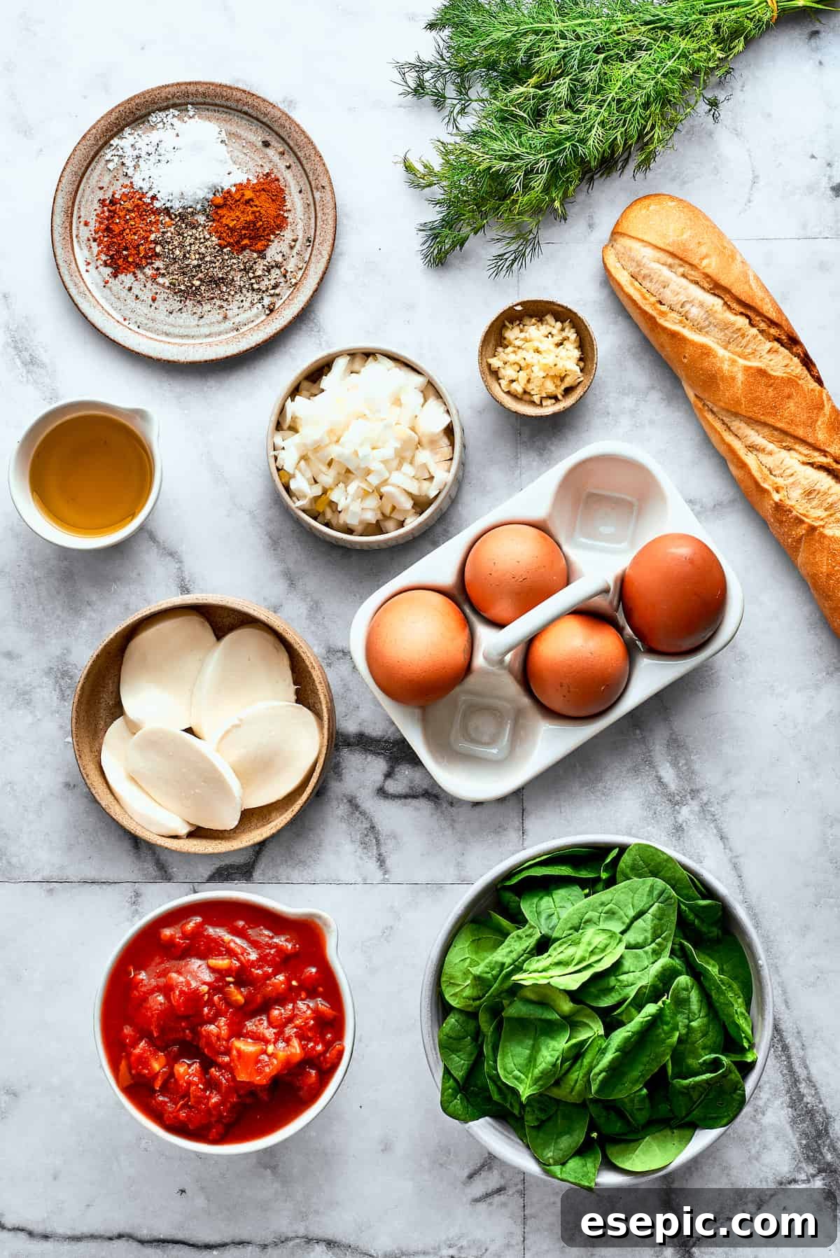 The ingredients for eggs in purgatory are shown on a white background: eggs, bread, fresh mozzarella cheese, spinach, diced tomatoes, garlic, olive oil, spices, dill.