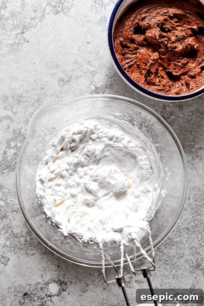 Whipped cream ready to be folded into the chocolate filling. A bowl of freshly whipped heavy cream sits beside a bowl of the rich chocolate filling, ready for the final step of incorporation.