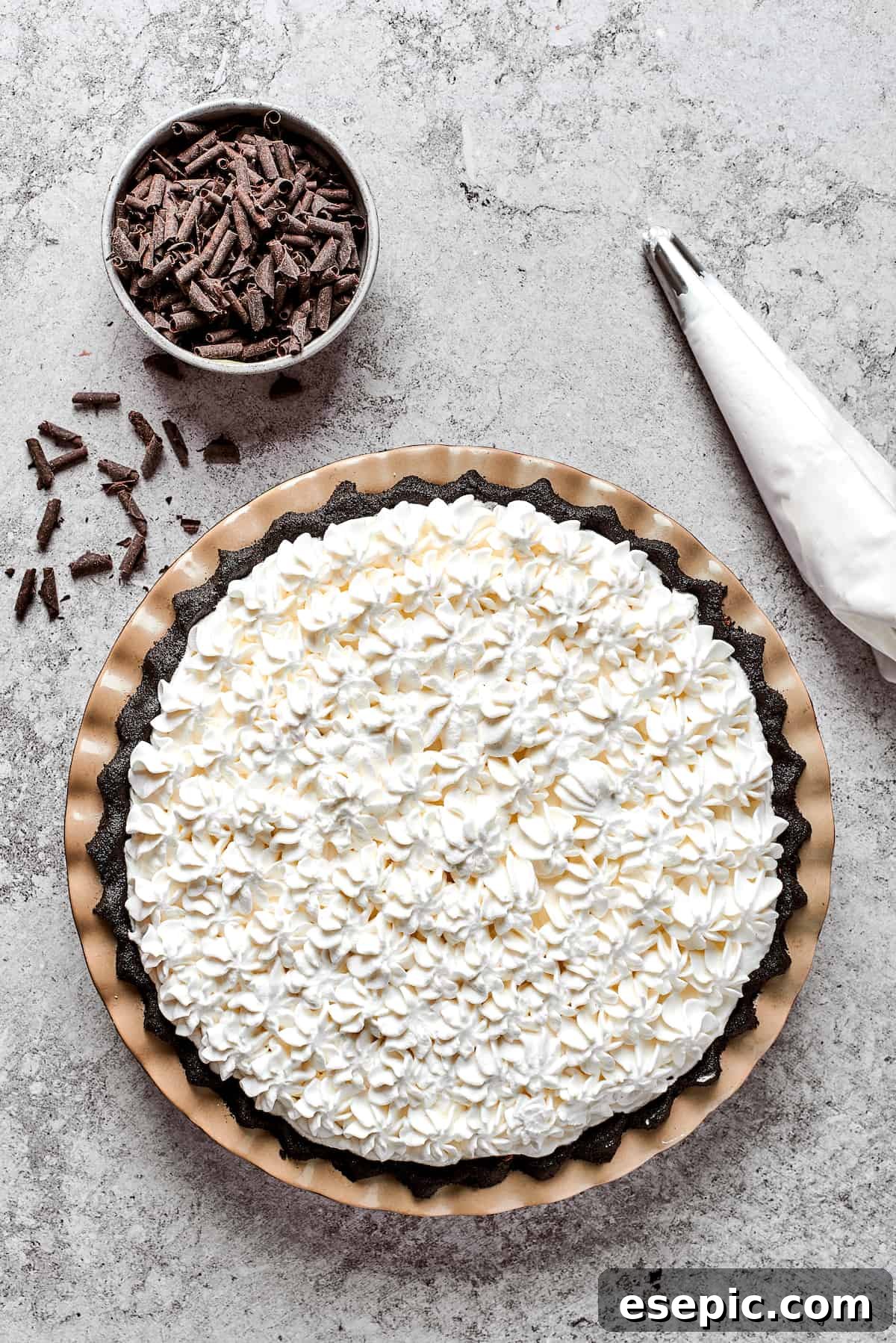 A beautifully decorated French Silk Pie, ready to be chilled and served. The finished French Silk Pie, generously topped with artfully piped swirls of homemade whipped cream and sprinkled with chocolate curls.