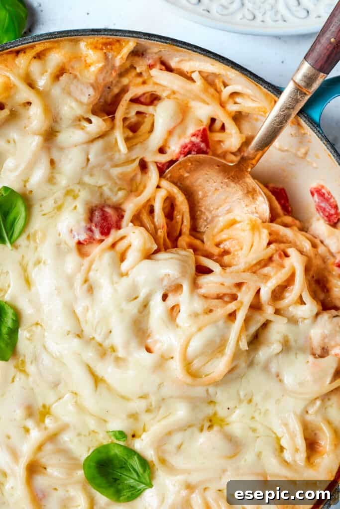 Serving a hearty scoop of cheesy chicken spaghetti A spoon digs into a bubbling pot of cheesy chicken spaghetti, showing the melted cheese and tender pasta.