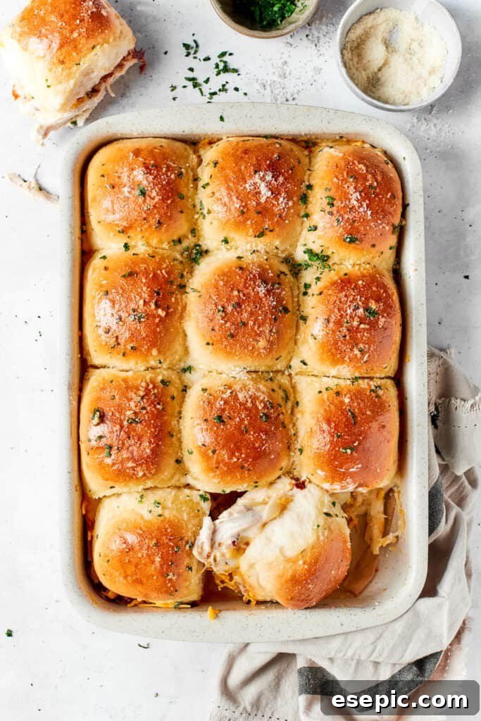 A pan of freshly baked chicken bacon ranch sliders on a rustic wooden table, garnished with parsley.