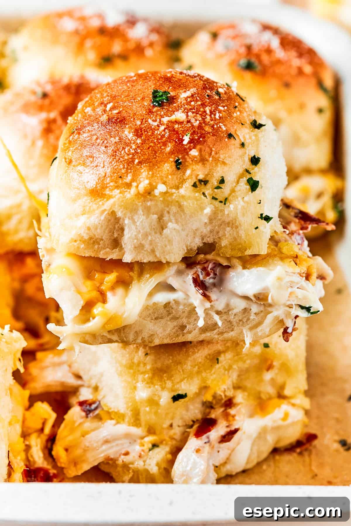 Two stacked chicken bacon ranch sliders showing the layers of chicken, bacon, ranch, and cheese between soft rolls.